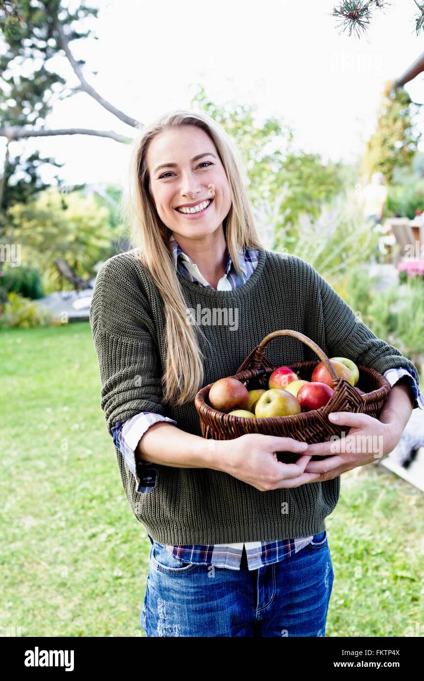 Mujer adulta media holding cesta de manzanas, Retrato Foto de stock
