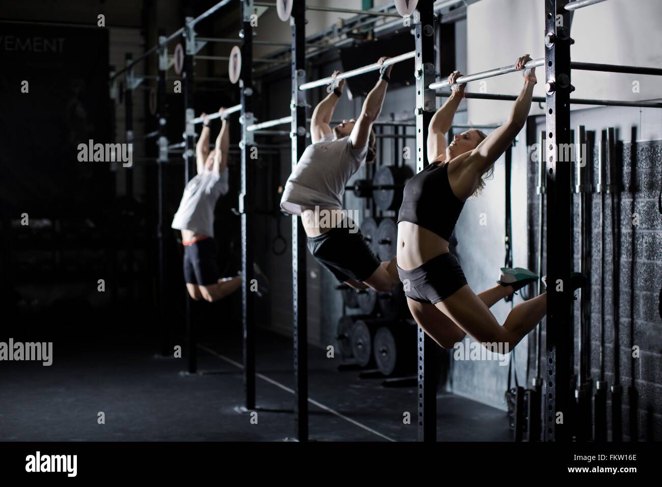 Machos y hembras adultos jóvenes capacitación en barra de pared en el gimnasio Foto de stock
