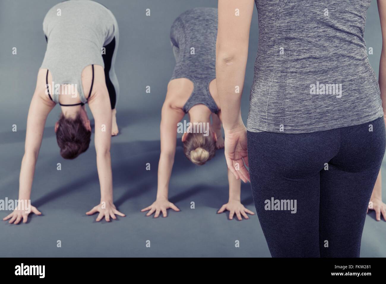 Las mujeres jóvenes practicando yoga, fondo gris Foto de stock