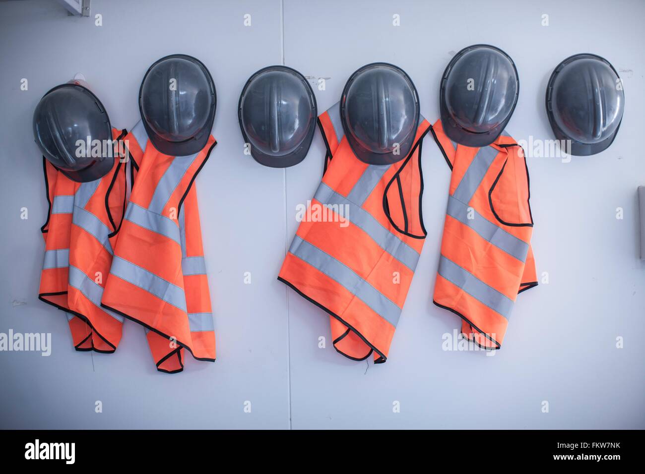 Filas de cascos y chalecos de alta visibilidad en la cabina portátil Foto de stock