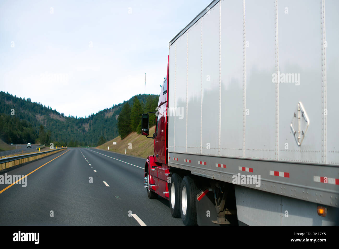 Rojo grande y moderno semi camión con remolque se apresuraron a un punto en el horizonte, que converge en la autopista multi-carril que cabalga carretilla con marcas de línea Foto de stock