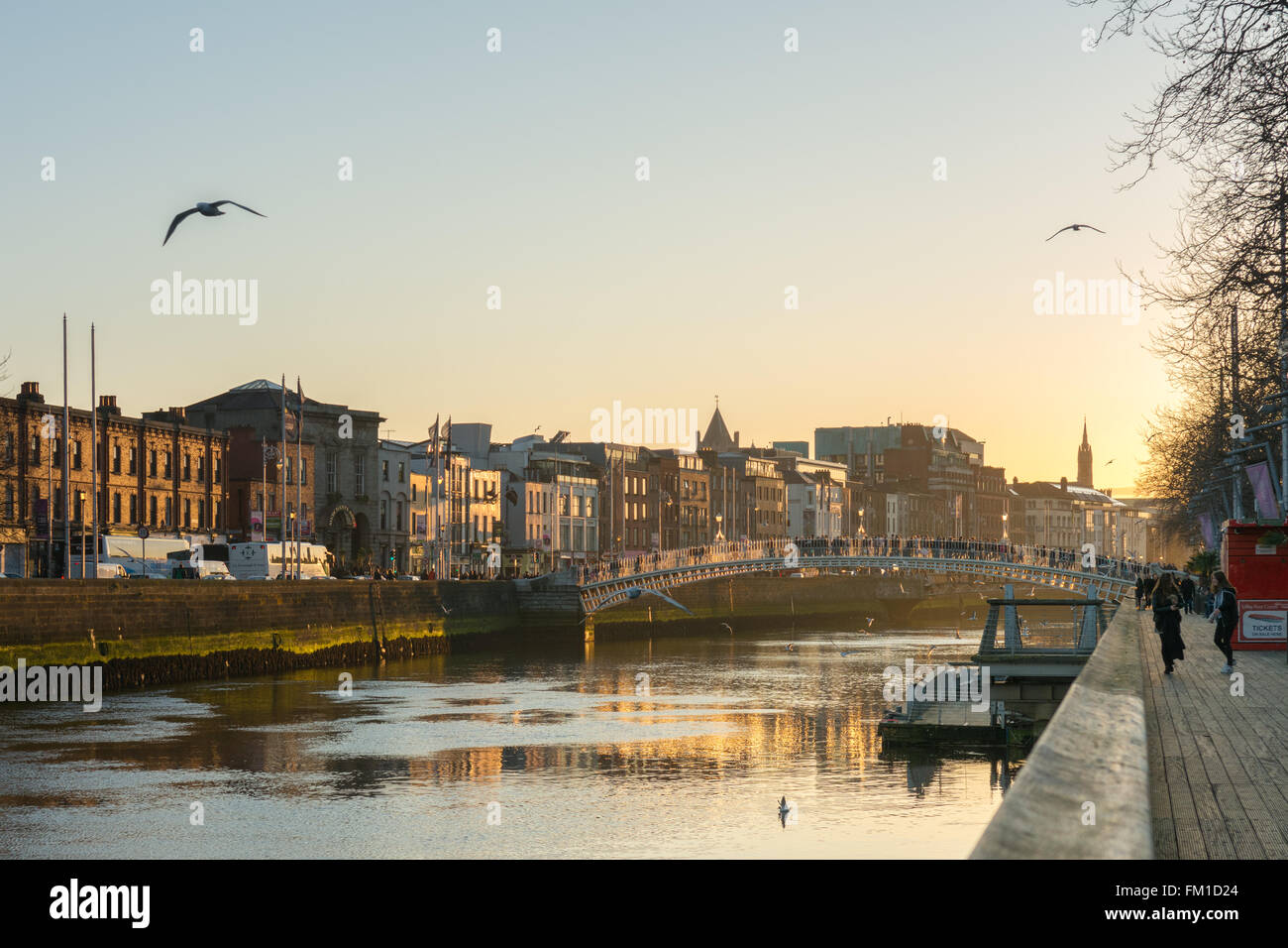 Dublín Irlanda en el ocaso: turistas de pie en el Ha'Penny Bridge viendo la puesta de sol sobre el río Liffey Foto de stock