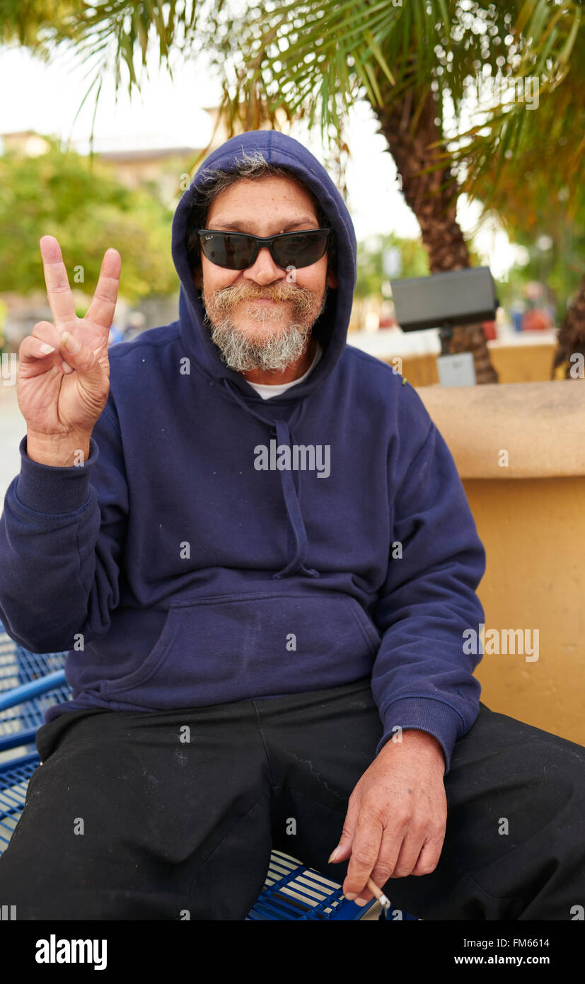 Hombre de fumar con barba gris y gafas de sol y haciendo el signo de la paz Foto de stock