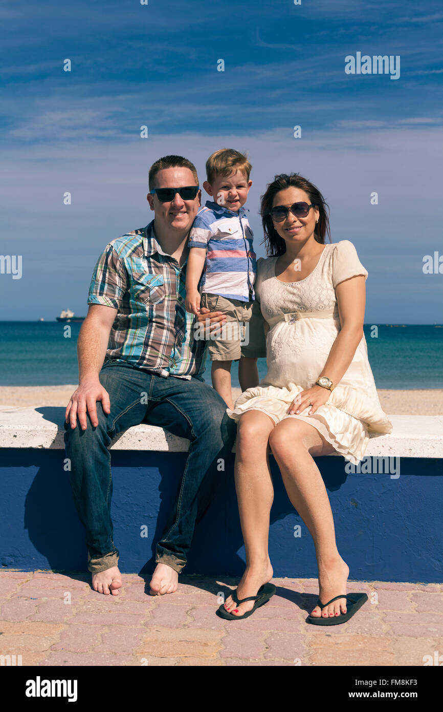Feliz pareja embarazada y su hijo disfrutar de días soleados en la costa de España. Foto de stock