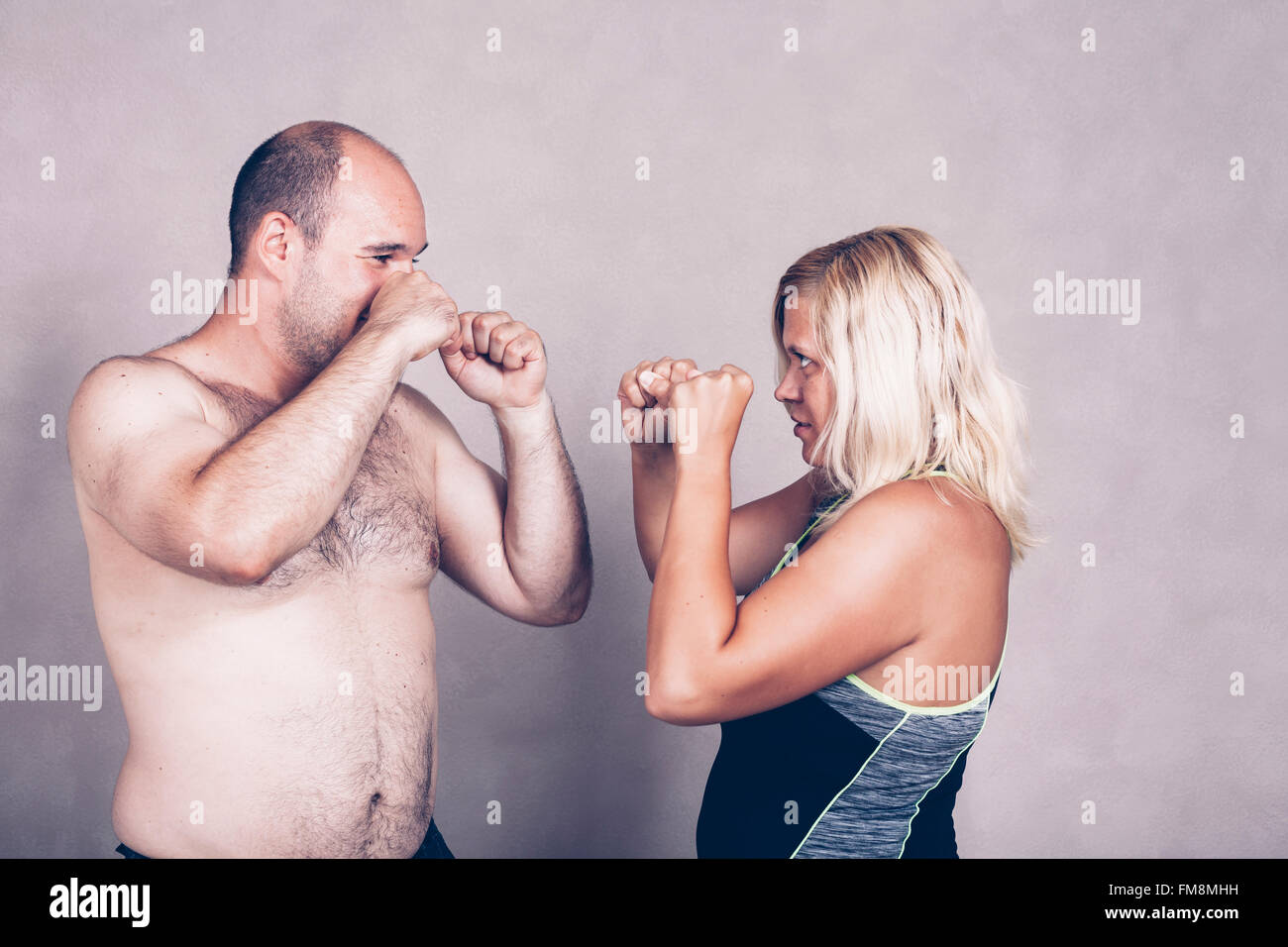 Descamisados corpulentos hombre y mujer de pie unos contra otros dispuestos a luchar. Foto de stock