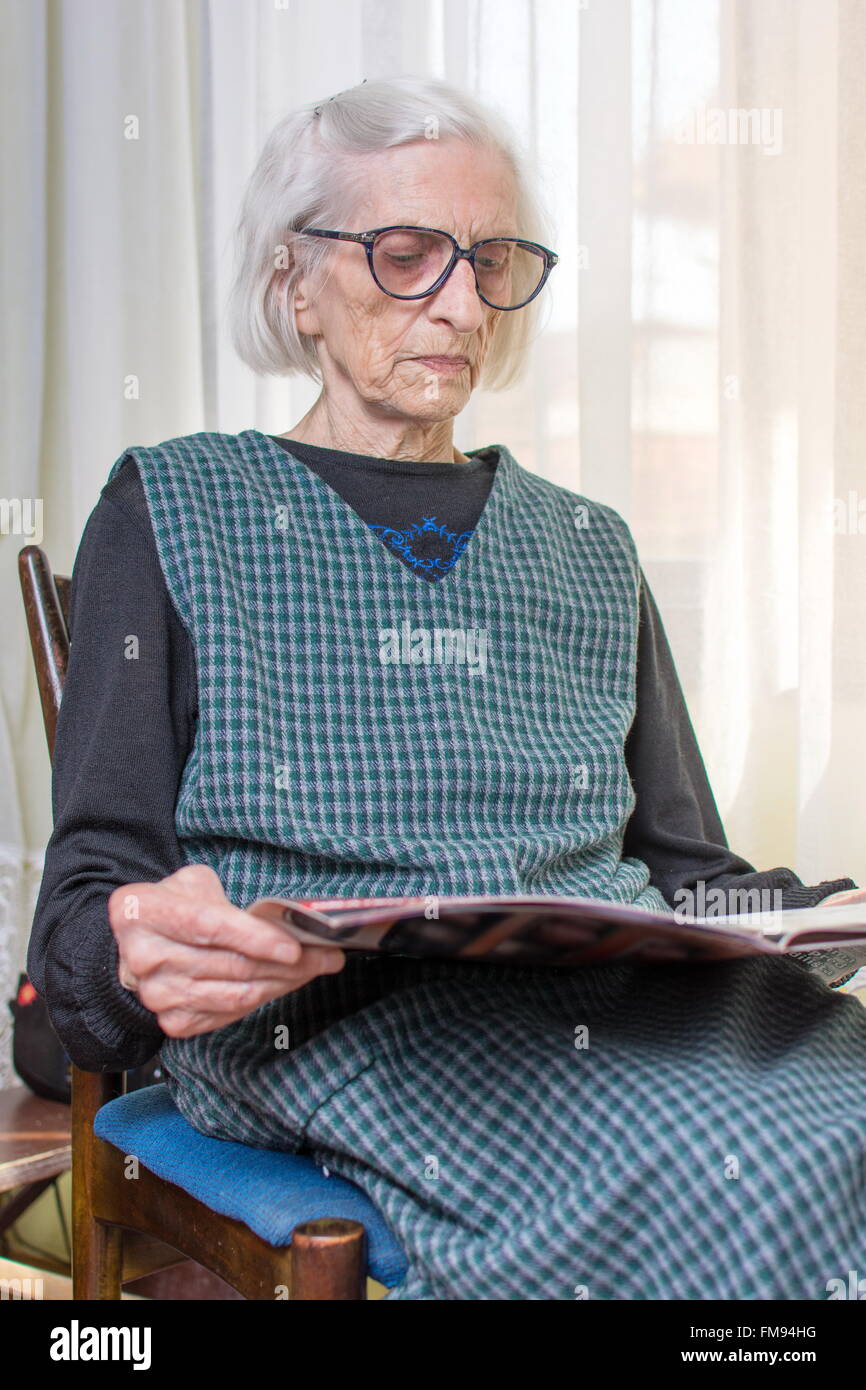 90 años dama leyendo periódicos en interiores Foto de stock