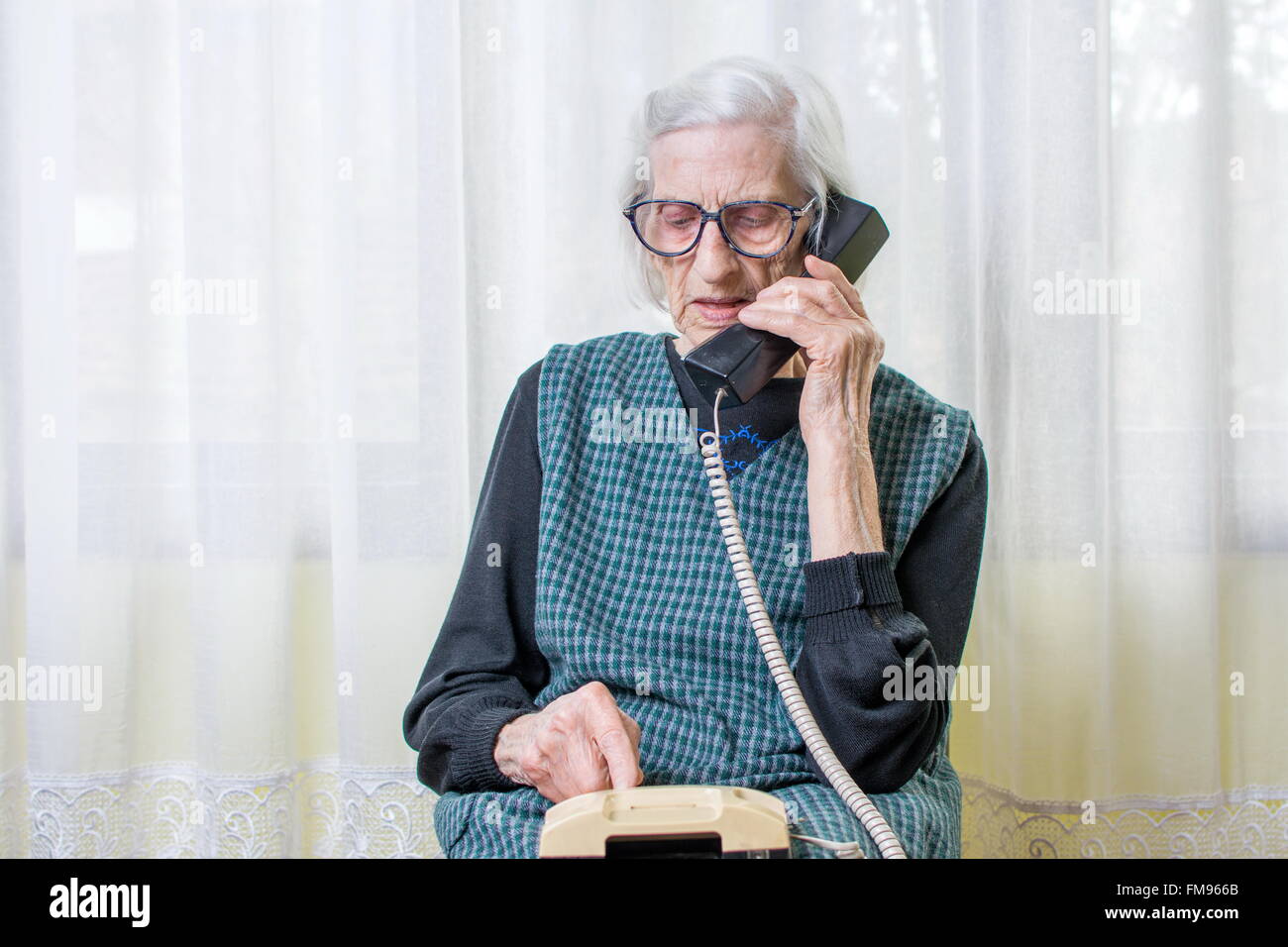 Mujer de 90 años de edad mujer utilizando el teléfono adentro Foto de stock