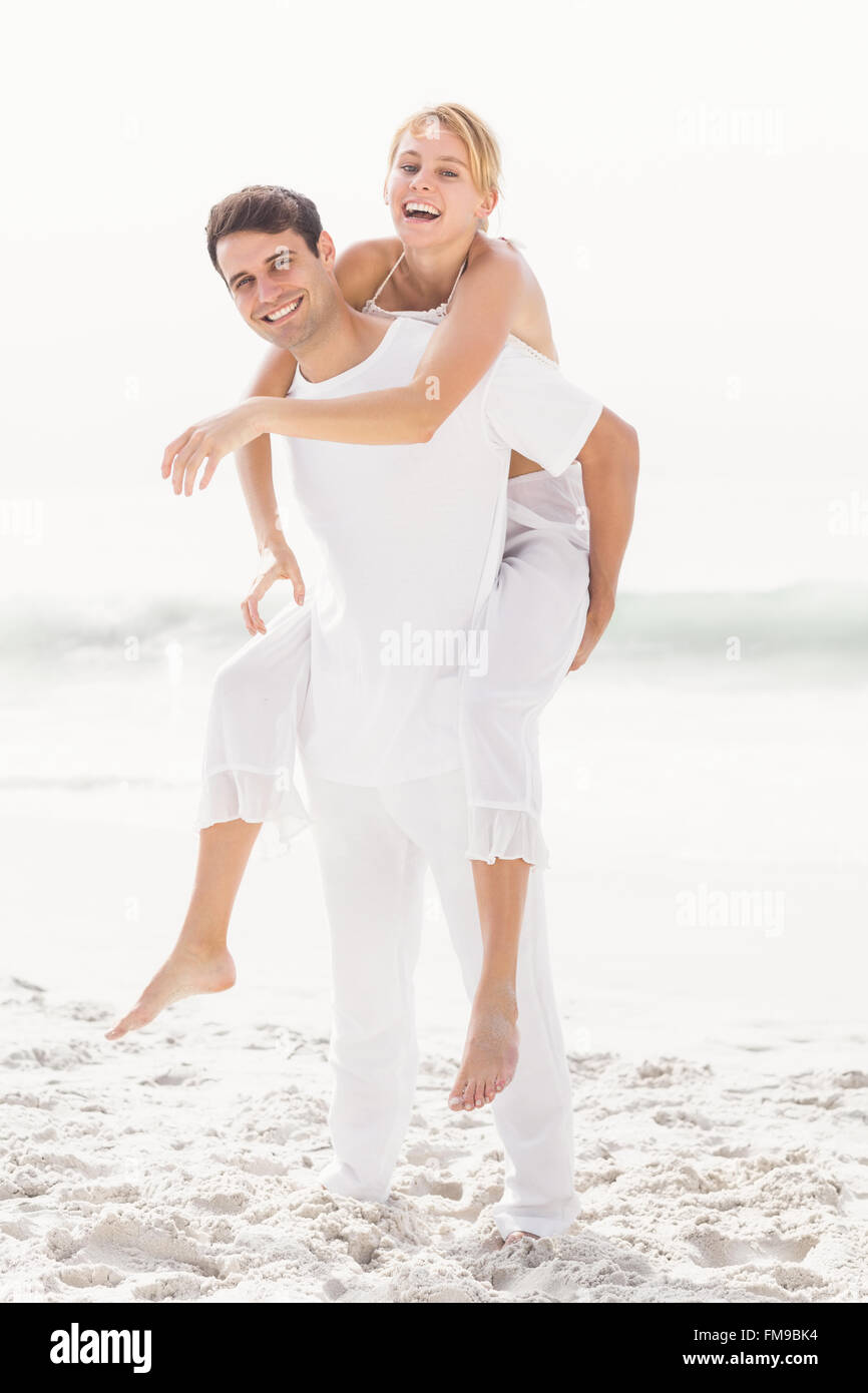 Hombre haciendo un piggy back a mujer en la playa Foto de stock