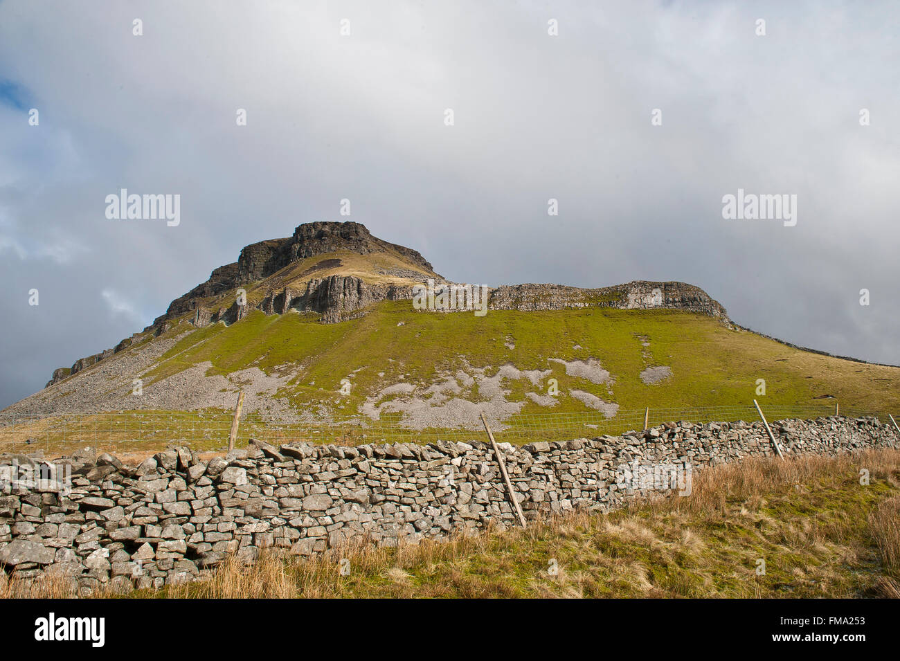 Pen-y-gent la montaña en invierno en Yorkshire Dales con muro de piedra seca y pavimento de piedra caliza de 3 picos sendero Foto de stock