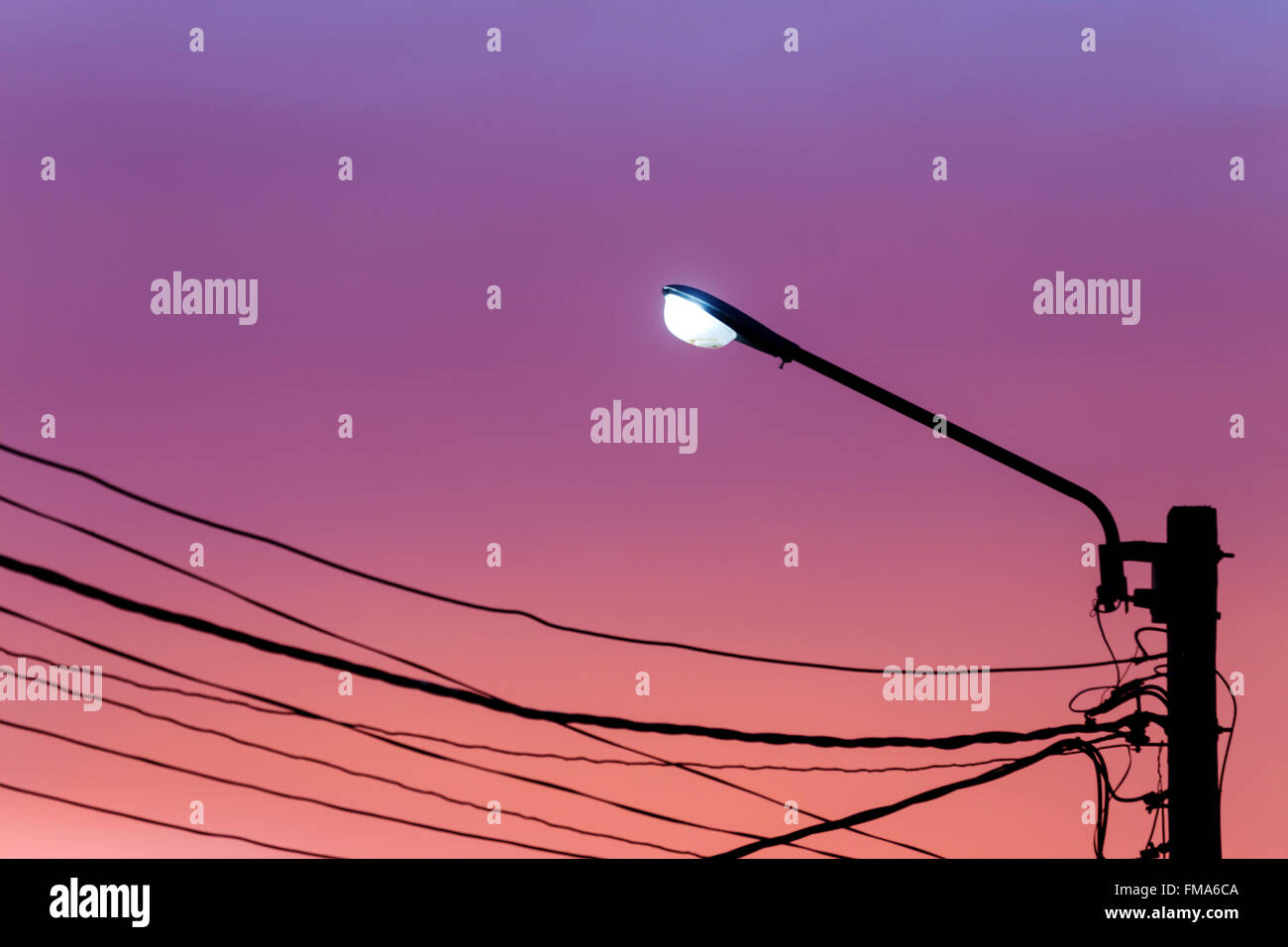Poste de luz de la calle con cable línea contra el fondo del cielo crepuscular Foto de stock