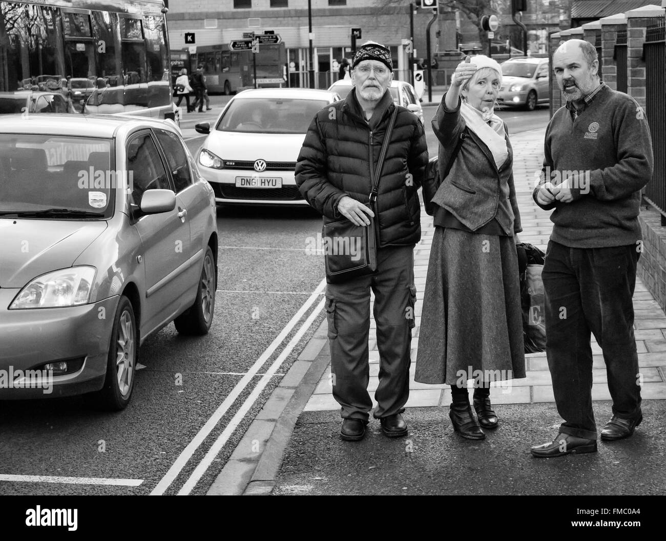 Pareja de ancianos dando instrucciones a un peatón en una calle con mucho tráfico, en Salisbury, REINO UNIDO Foto de stock