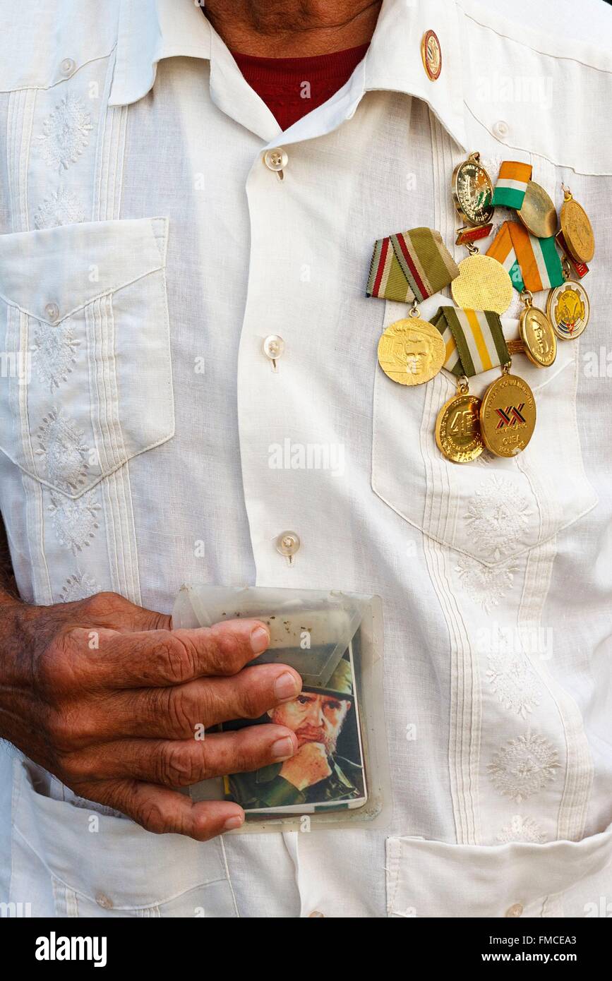 Cuba, Villa Clara, Santa Clara, Hombre sujetando medallista en la mano una foto de Fidel Castro Foto de stock