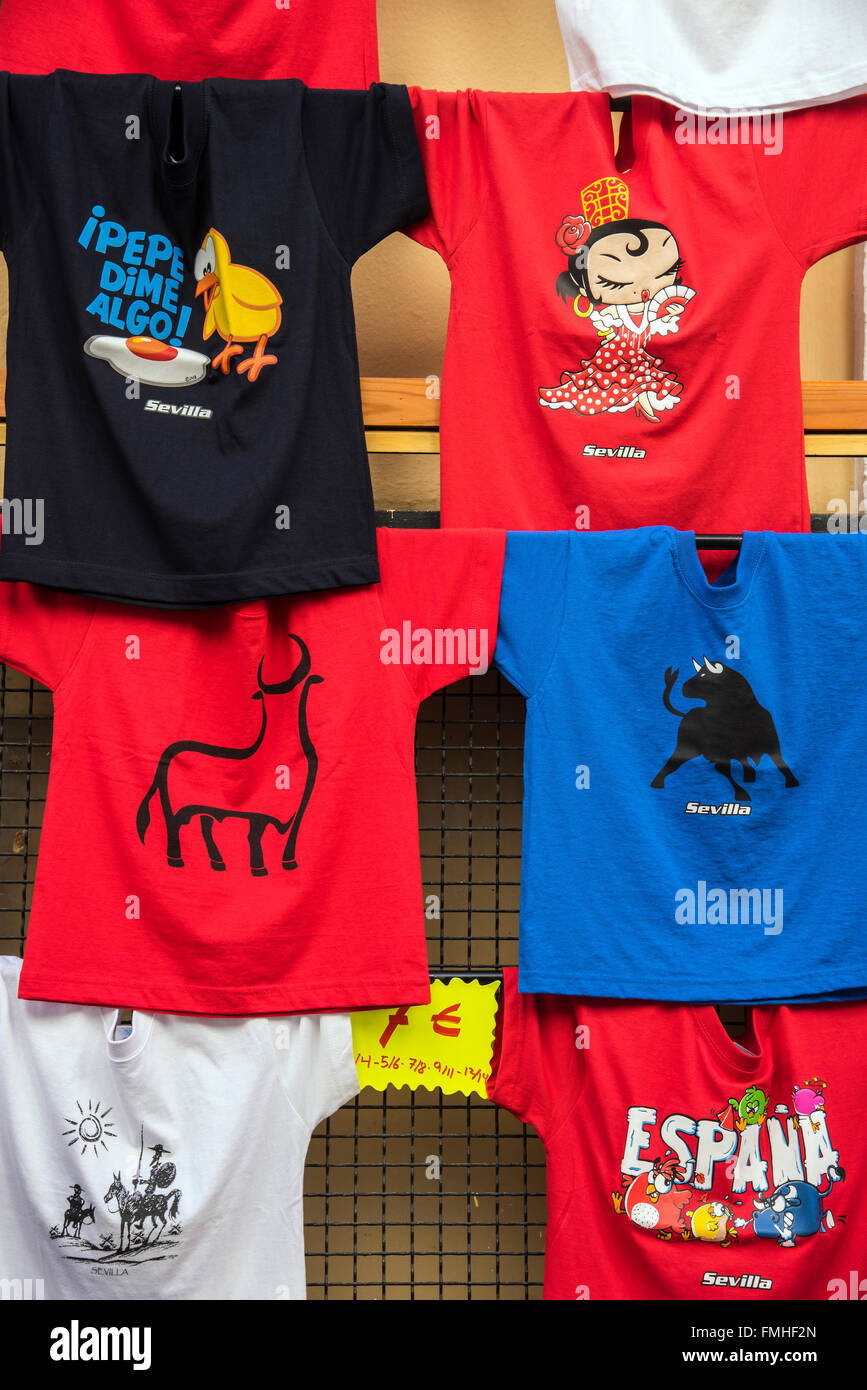 Las camisetas coloridas en venta en una tienda de barrio de Santa Cruz, Sevilla, Andalucía, España Foto de stock