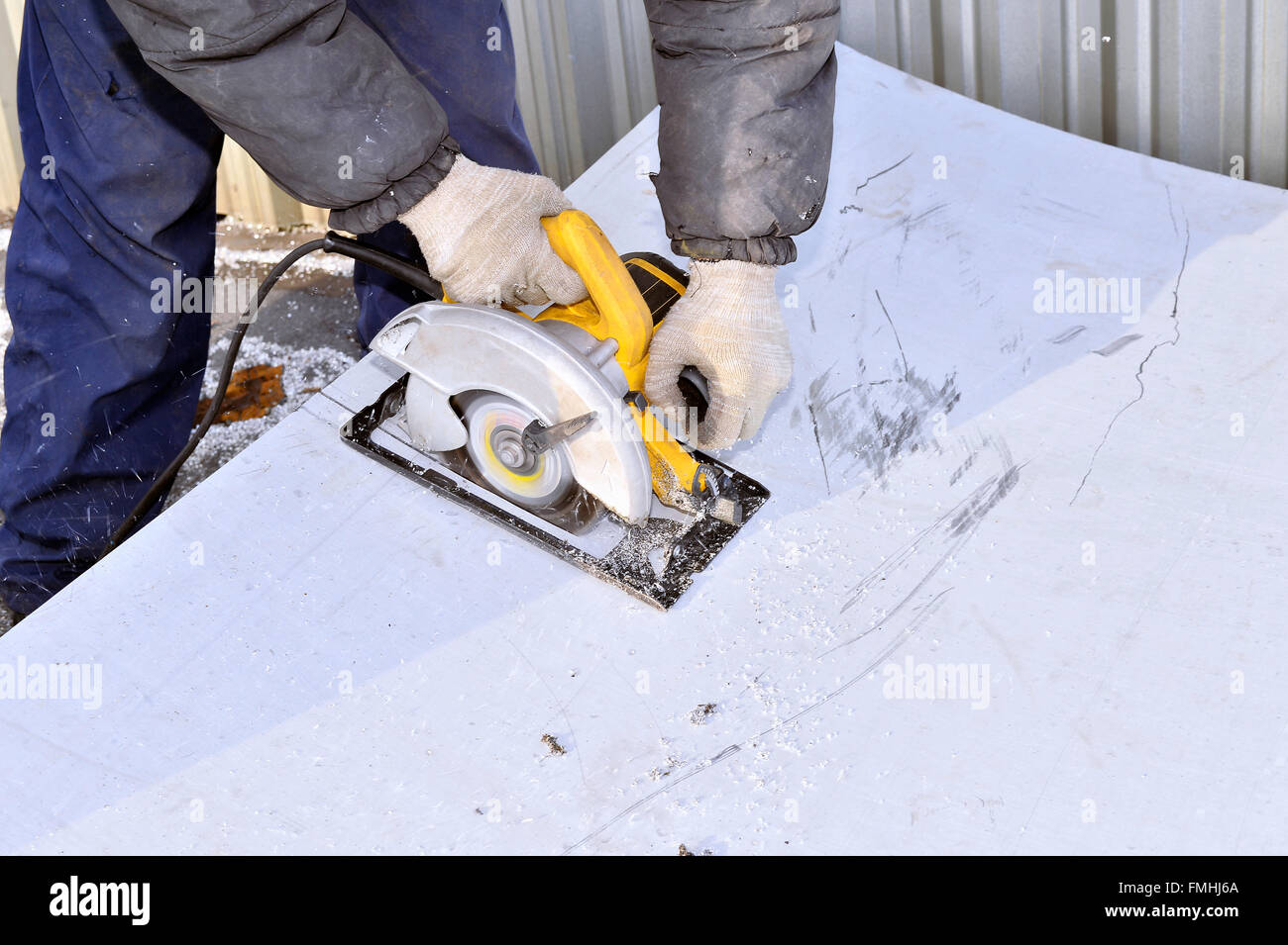 Herramienta eléctrica de mano en manos del trabajador, cortando hoja de metal. Foto de stock