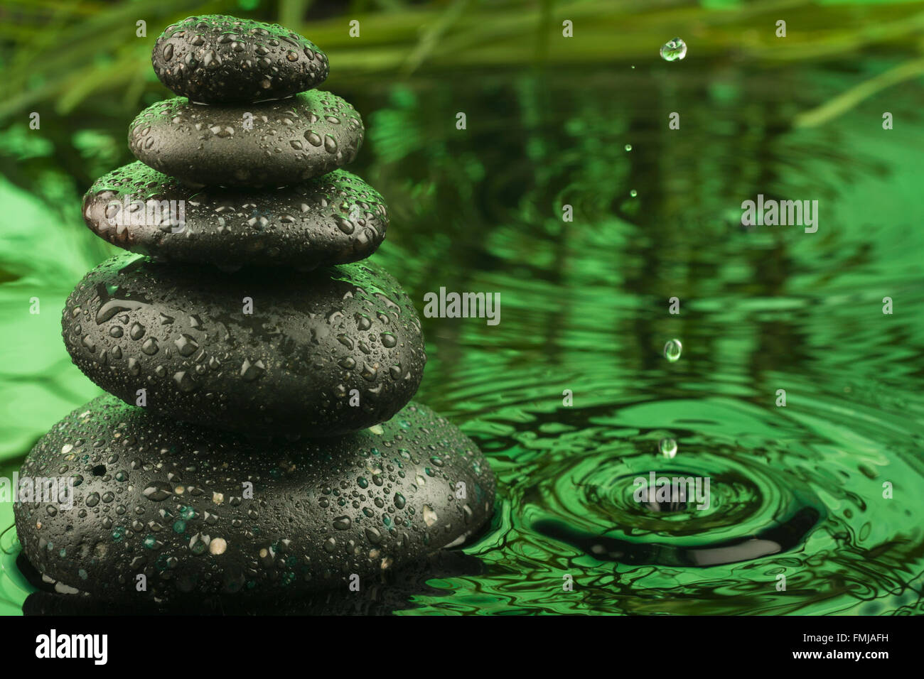 Pirámide de piedras y una caída en el agua verde, como fondo Foto de stock