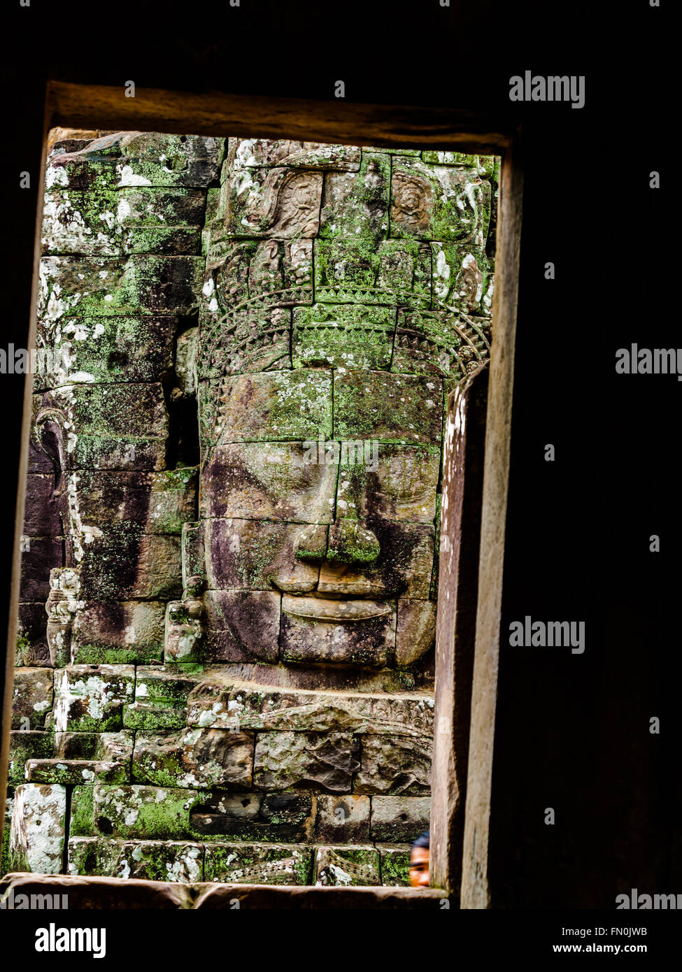 La antigua piedra tallada de cara sonriente en el templo Bayon en Siem Reap, Camboya Foto de stock
