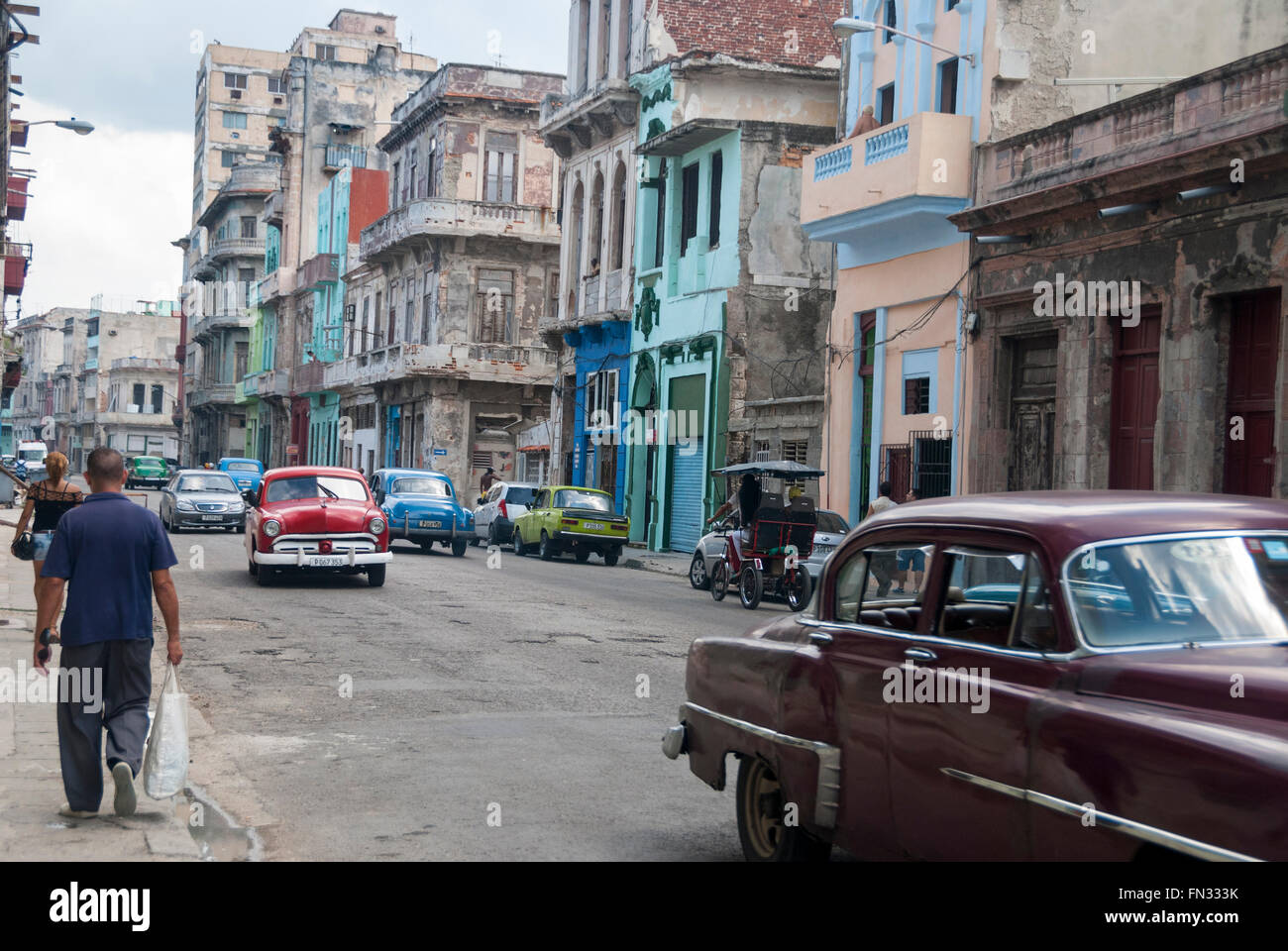 Los edificios ruinosos y vintage coches americanos usados como taxis son un espectáculo común en el distrito central de La Habana. Foto de stock