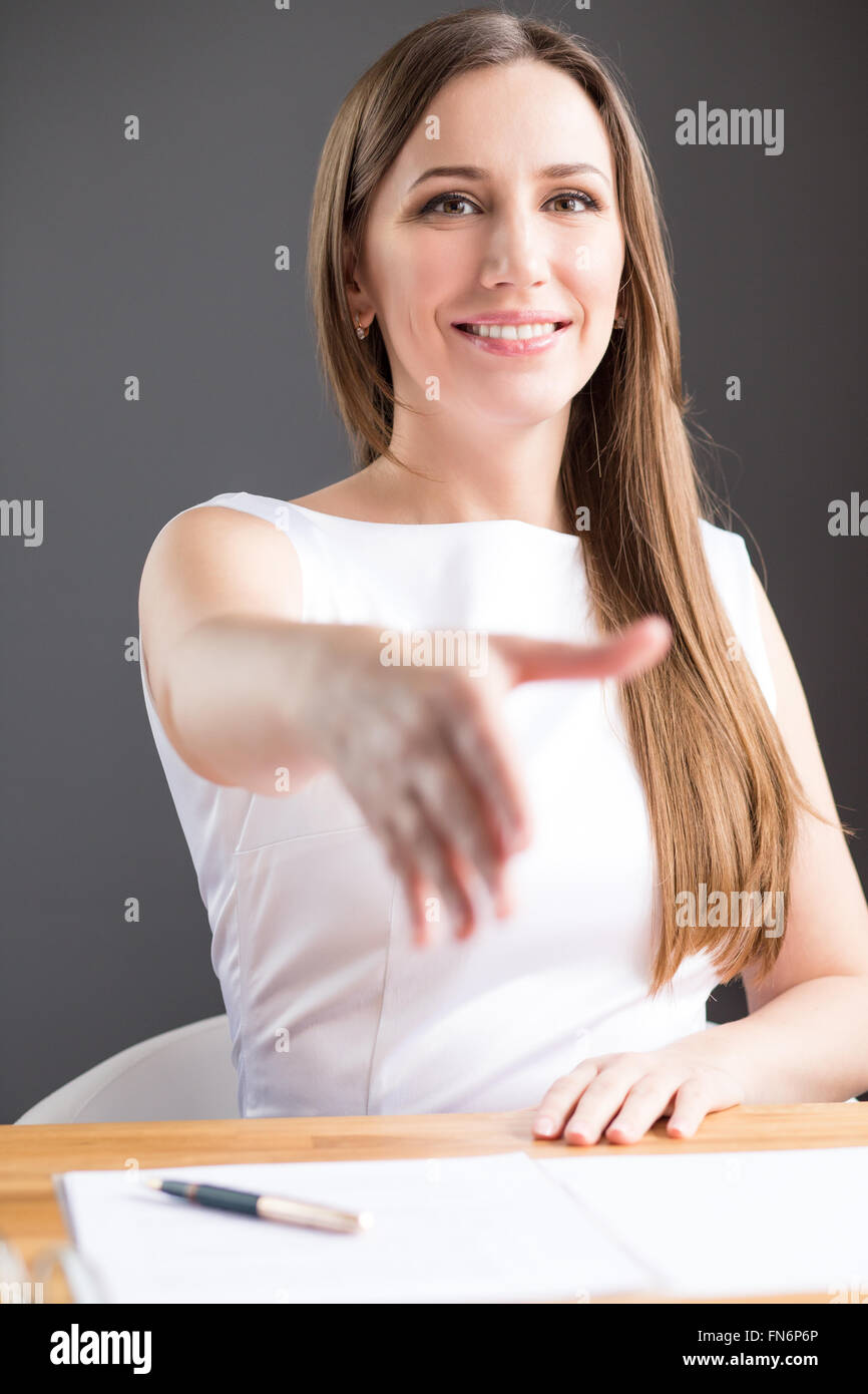 Joven mujer de negocios feliz en vestido blanco reunión socio para las negociaciones en su oficina Foto de stock