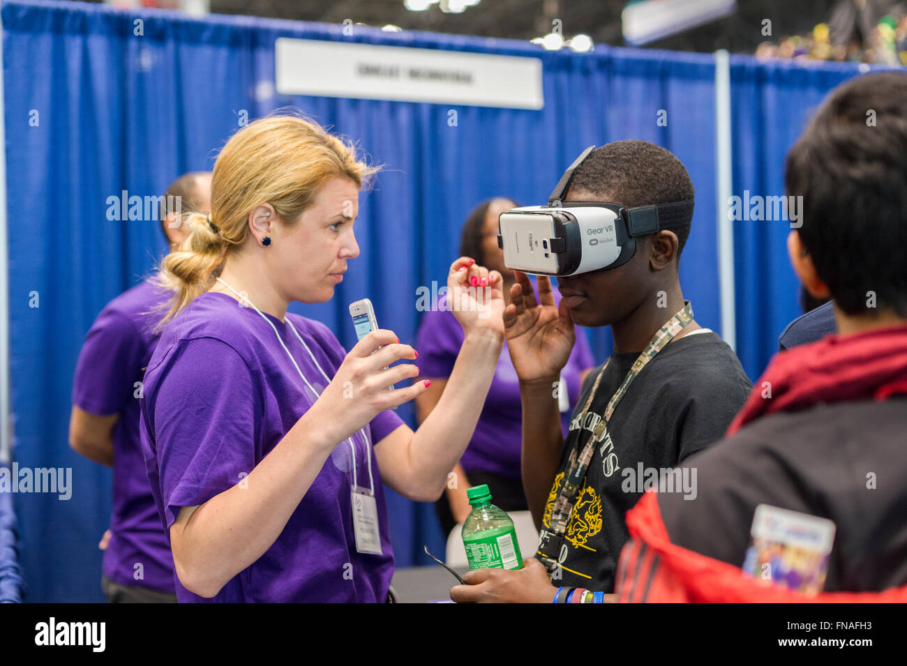 Un trabajador de Comcast NBCUniversal asiste a un visitante con un engranaje de Samsung VR Dispositivo de realidad virtual en una carrera Expo celebrada en el primer campeonato de NYC de robótica en el centro de convención de Jacob Javits en Nueva York el domingo, 13 de marzo de 2016. La expo permite a los participantes hablar con empresas y organizaciones profesionales dando una mirada del mundo real en la ciencia y la tecnología, tal como se utiliza en el mundo de los negocios y sus oportunidades de carrera. (© Richard B. Levine) Foto de stock