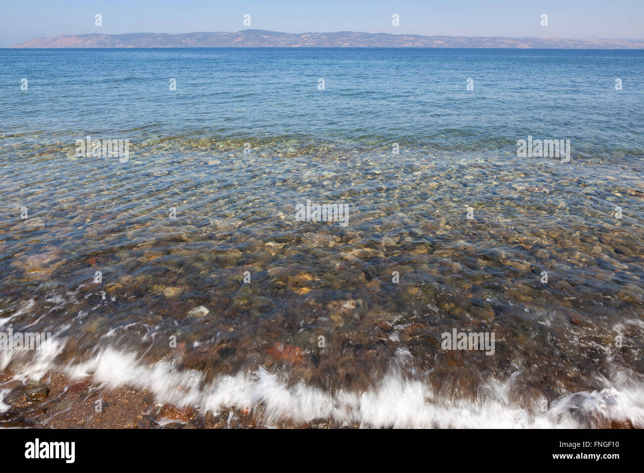 Las ondas de agua de mar clara sobre guijarros de lavado en el Mar Egeo Foto de stock