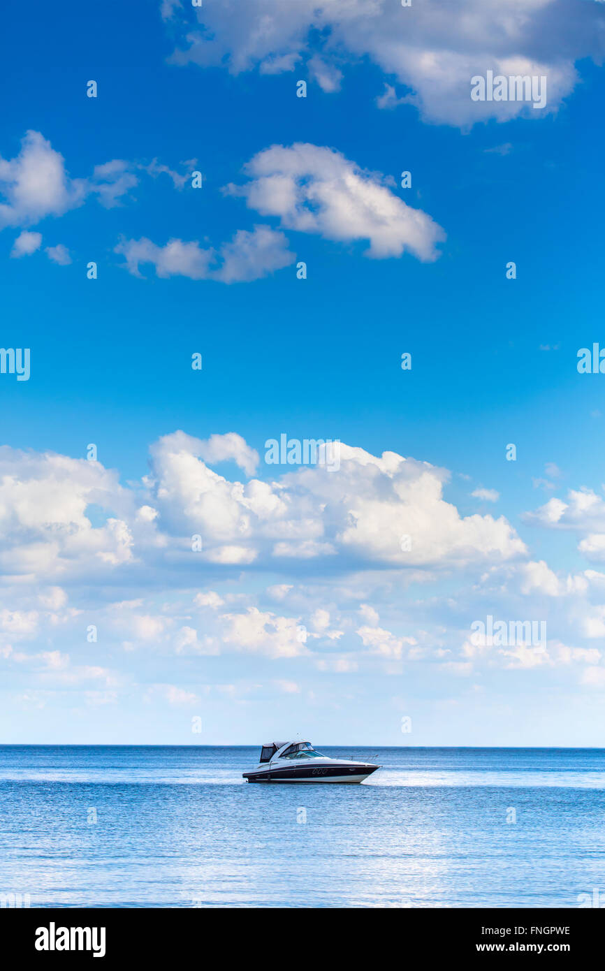 Barco en el tranquilo mar azul - con azul cielo nublado Foto de stock
