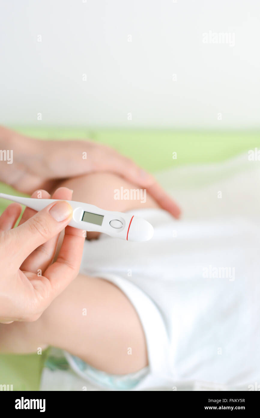 Comprobación de la temperatura del bebé que indica alta fiebre de termómetro Foto de stock