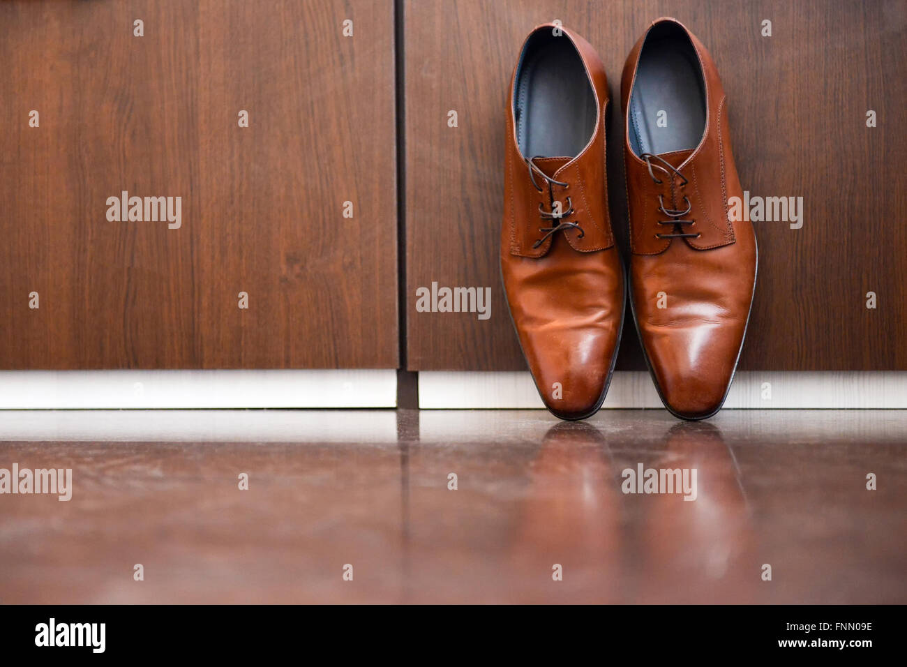 Zapatos de cuero marrón sentado sobre un piso de madera Foto de stock