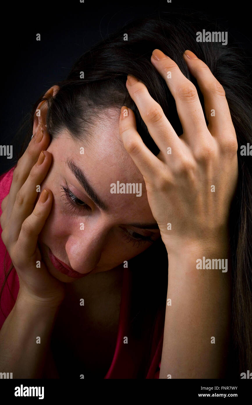 Un deprimido y triste mujer sostiene su cabeza en sus manos. Foto de stock