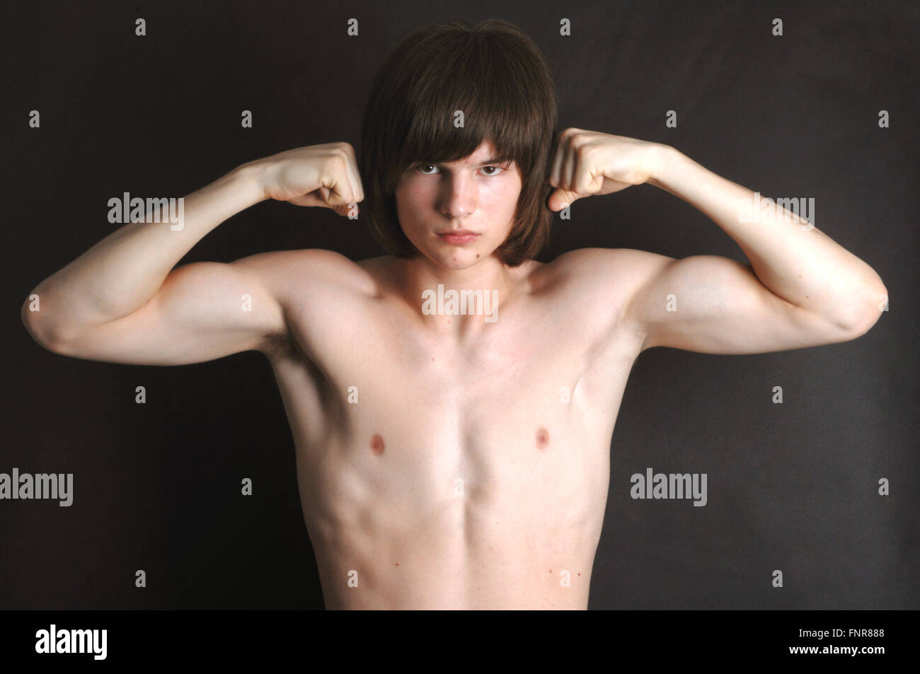 Bare chested adolescente flexiona sus músculos. Foto de stock