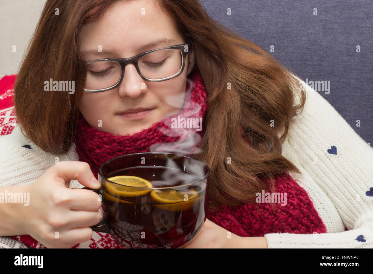 Mujer enferma llevar bufanda acostado en la cama bebiendo té Foto de stock