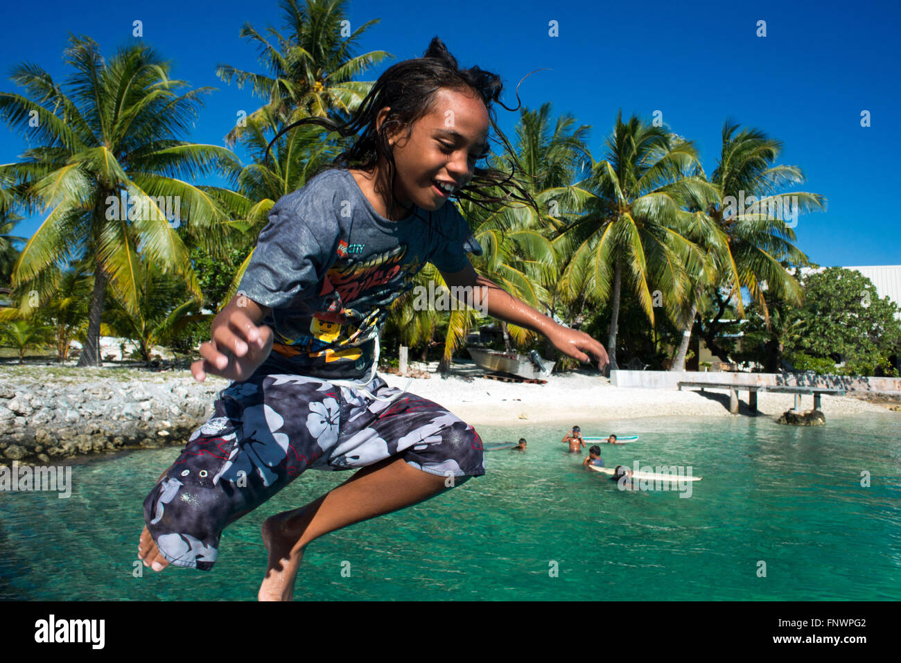 Playa de Rangiroa, las Islas Tuamotu, en la Polinesia Francesa, el Pacífico Sur. Un niño jugando y saltando en el agua. Foto de stock