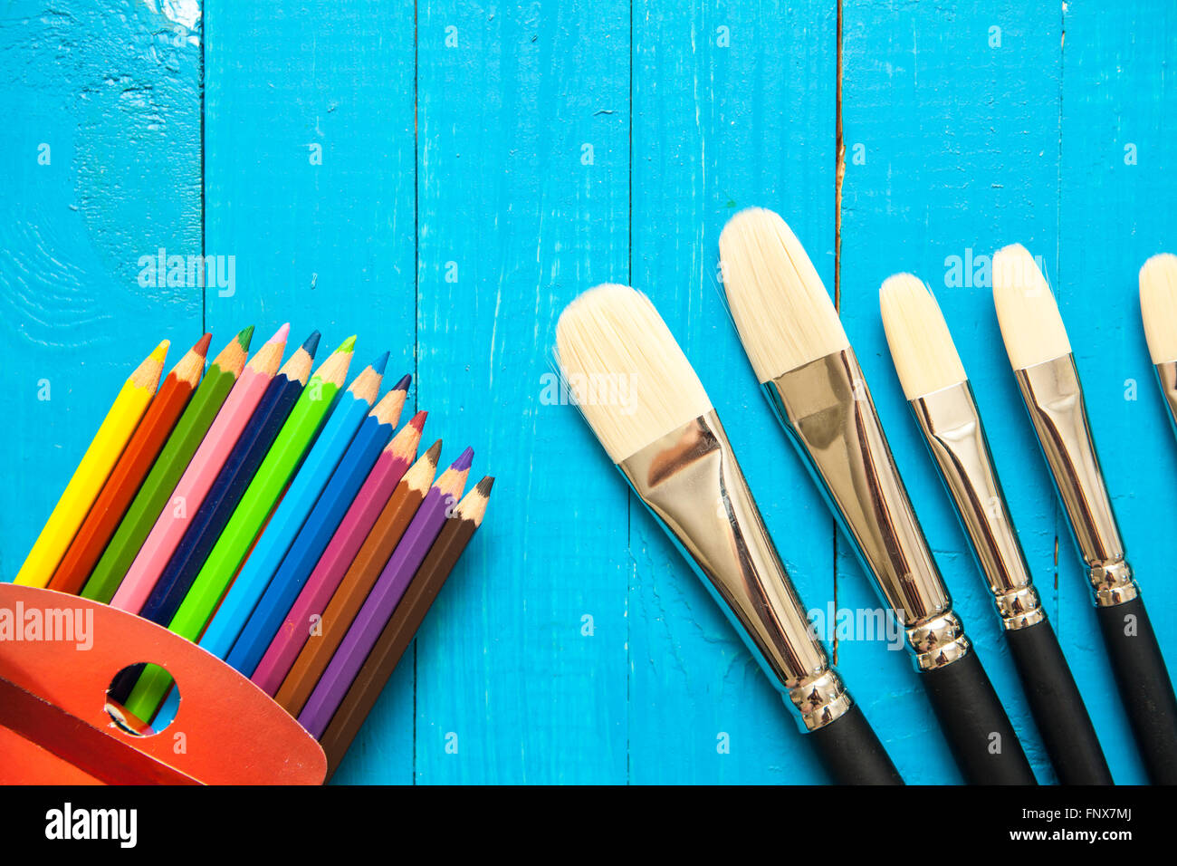 Pinceles y lápices de colores sobre un fondo de madera Foto de stock