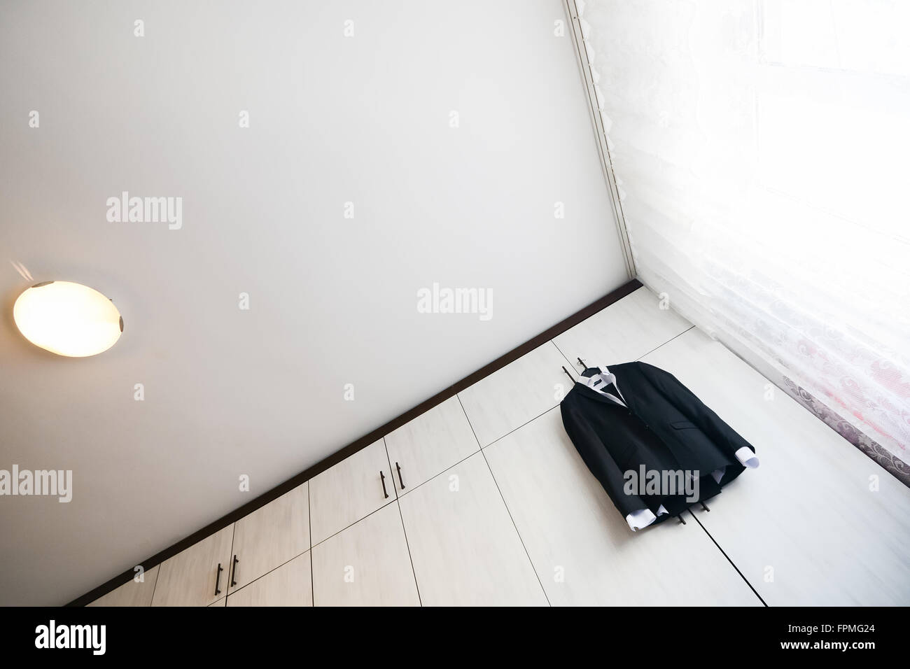 Traje negro con camisa colgando de un armario de madera Foto de stock