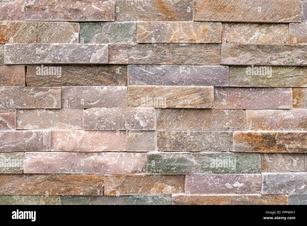 Detalle de un muro de piedra de tosca, mirando las piedras de colores pastel Foto de stock