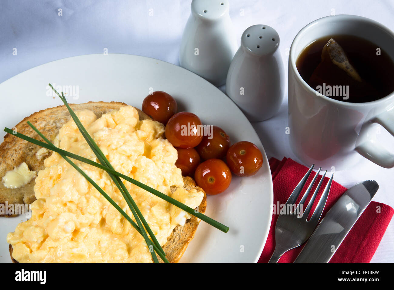 Vista de un típico desayuno inglés comida de huevos revueltos sobre  tostadas con tomate cherry al horno y una guarnición de cebolleta  Fotografía de stock - Alamy