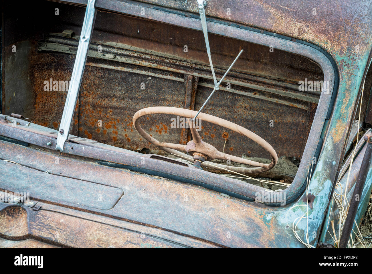 Basura coche oxidado, vista frontal con volante a través del parabrisas y limpiaparabrisas sin vidrio Foto de stock