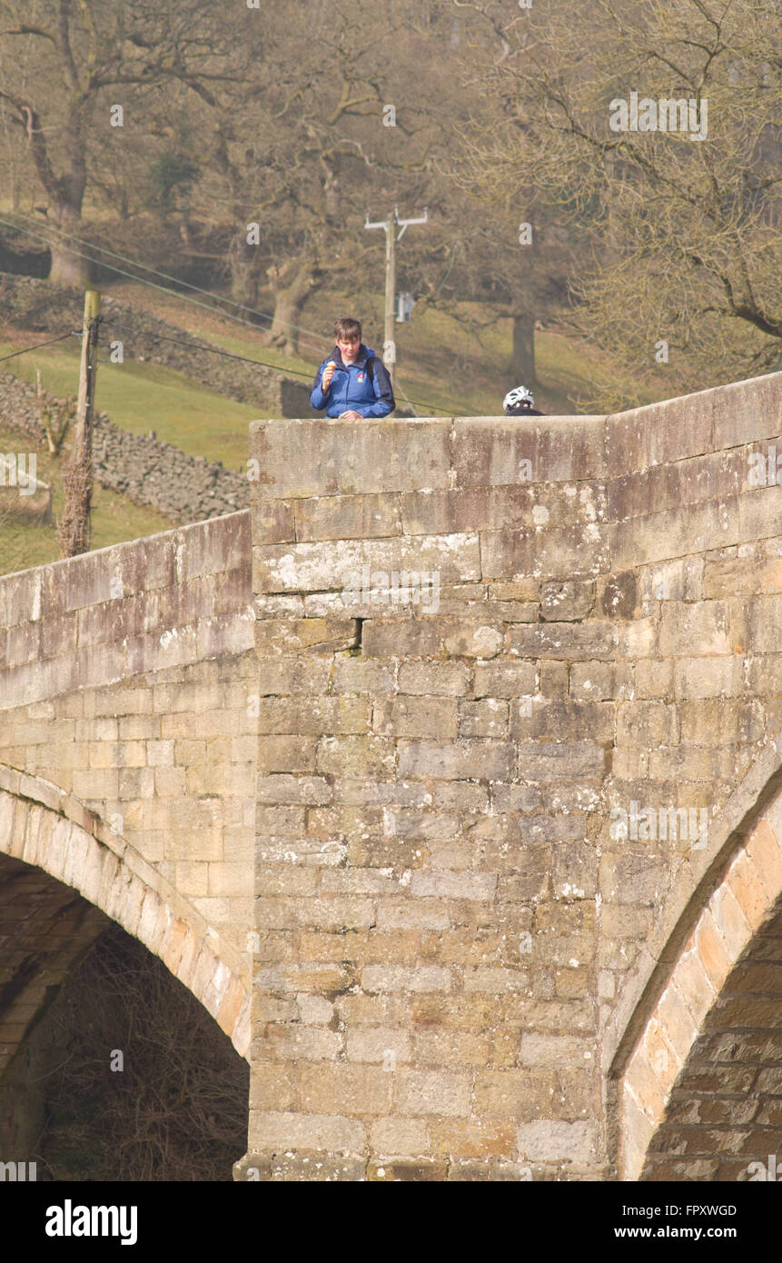 Mujer mirando por encima del parapeto del Puente Puente Barden Bolton Abbey Yorkshire Dales Uk Foto de stock