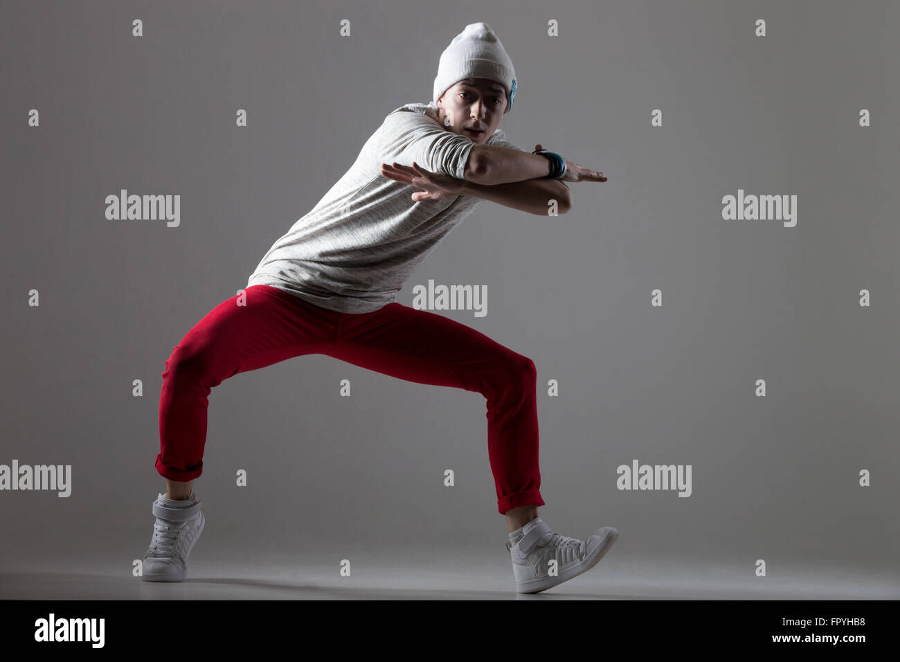 Retrato del bailarín moderno guy trabajando fuera vistiendo casual pantalones rojos y gorra. Estilo moderno de formación joven bailarina, bailando. Foto de stock