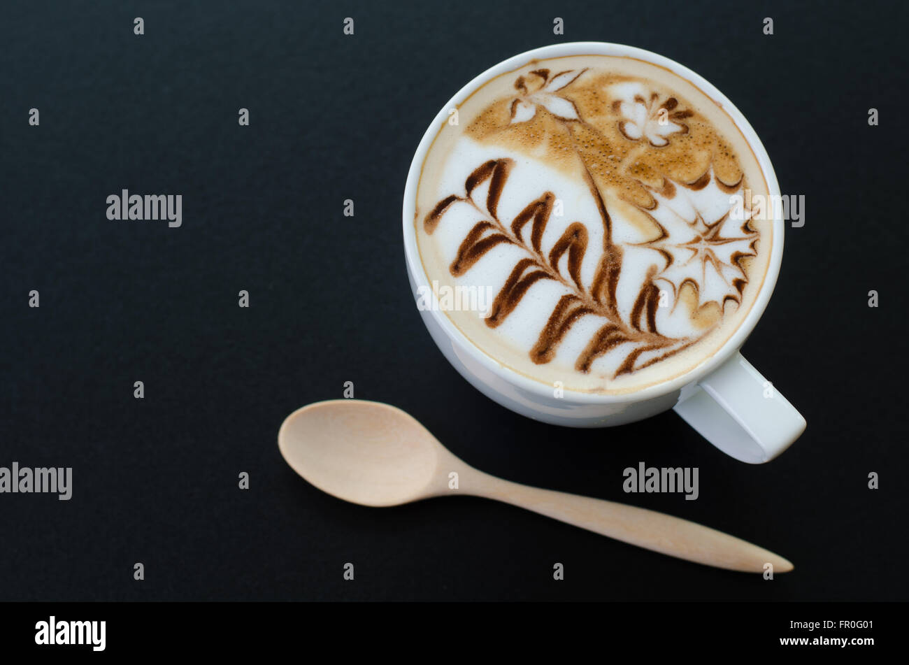 Una taza de café latte arte sobre fondo negro Foto de stock