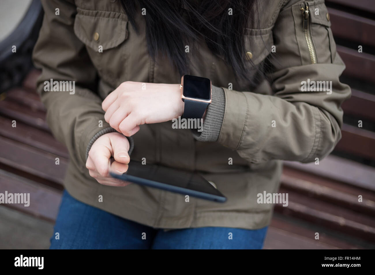 Niña con su moderno reloj de pulsera inteligente y tablet pc sentado en un  banco. Esa persona está siempre conectado a los medios de comunicación  social Fotografía de stock - Alamy