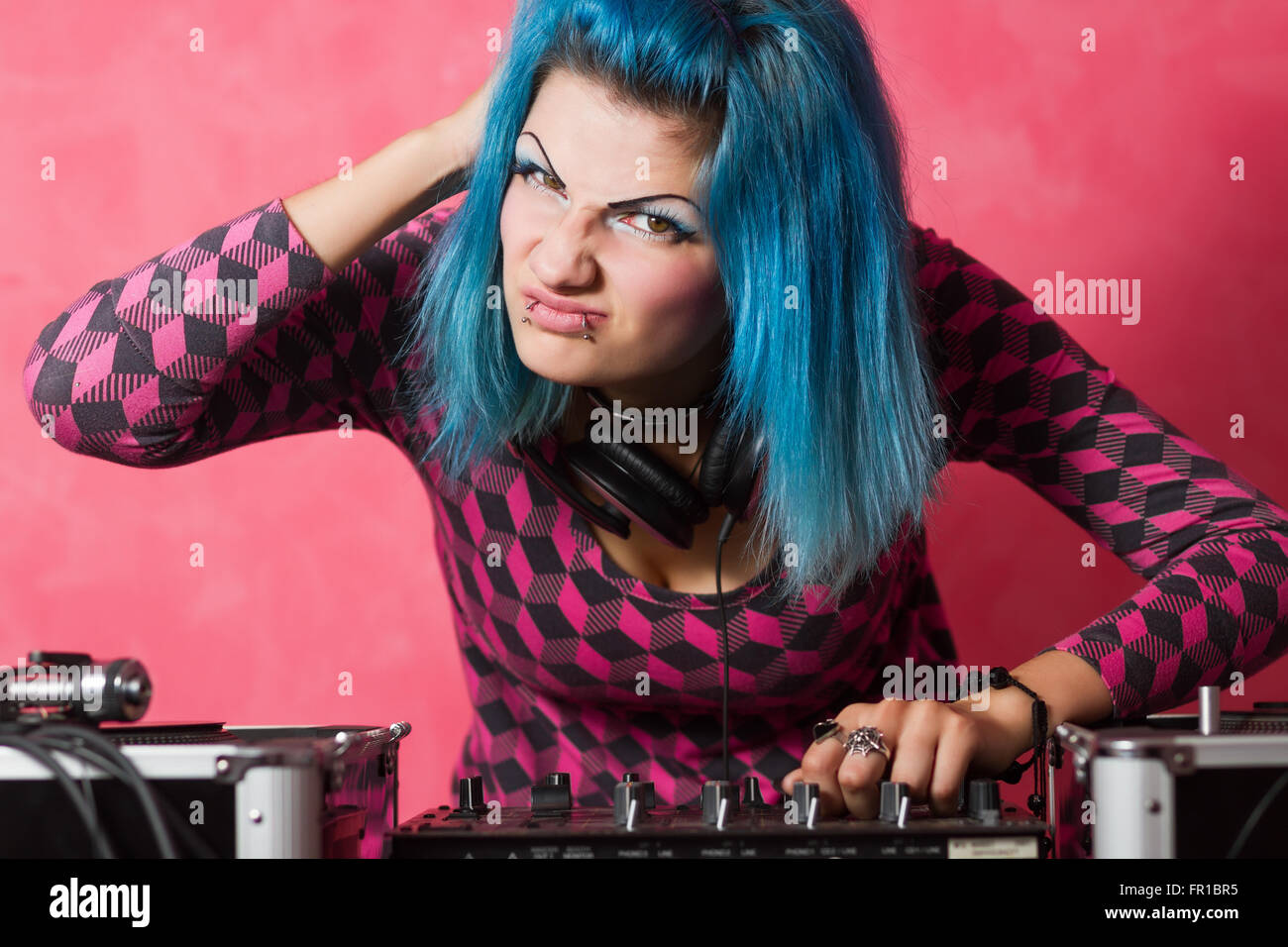 Linda chica con azul teñido de hari y traje rosa reproduciendo música registros en un equipo profesional Foto de stock