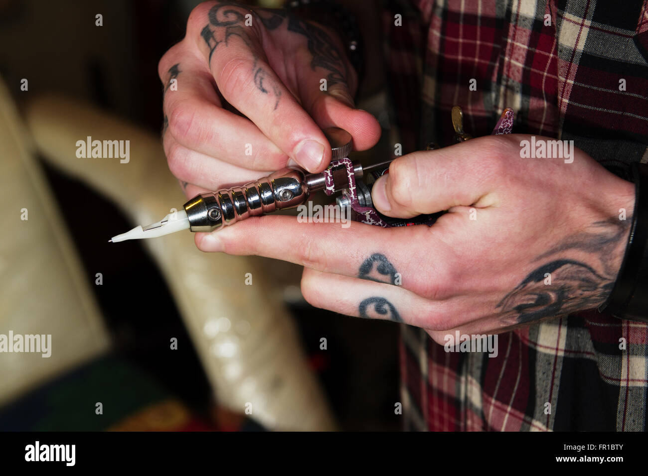 Máquina profesional para realizar un tatuaje en heavy tatuado las manos de un maestro Foto de stock