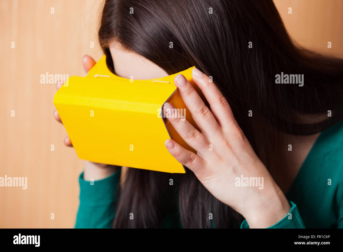 Retrato de una chica que llevaba casco de realidad aumentada de cartón emparejado con su teléfono inteligente. Foto de stock