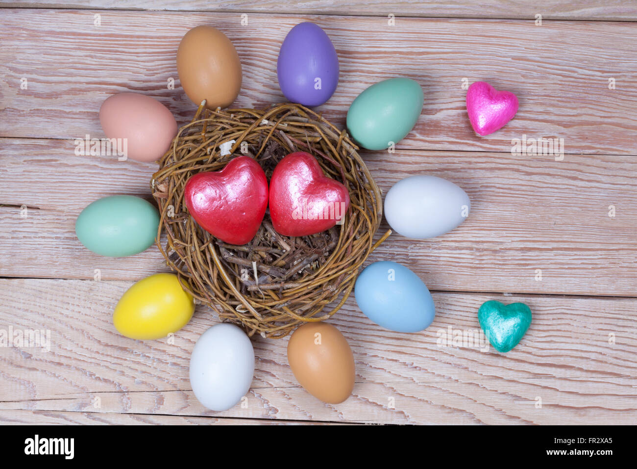 Montón de coloridos huevos de Pascua en el nido de pájaro sobre fondo de madera Foto de stock