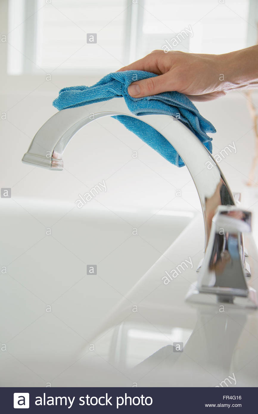Mujer pulido grifo del baño con paño de limpieza. Foto de stock