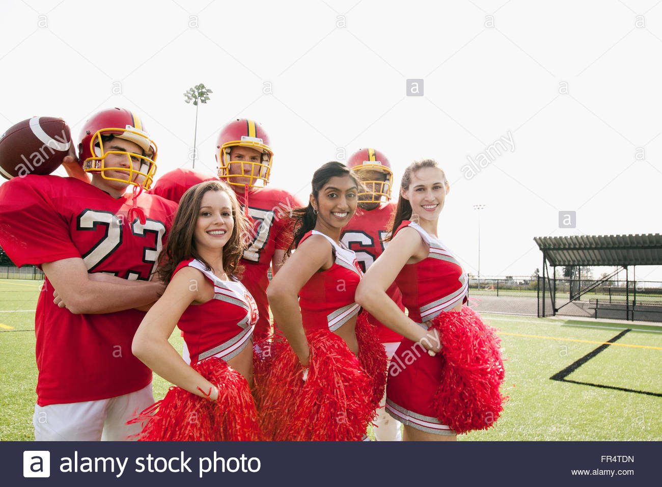 Los jugadores de fútbol americano universitario con cheerleaders Foto de stock