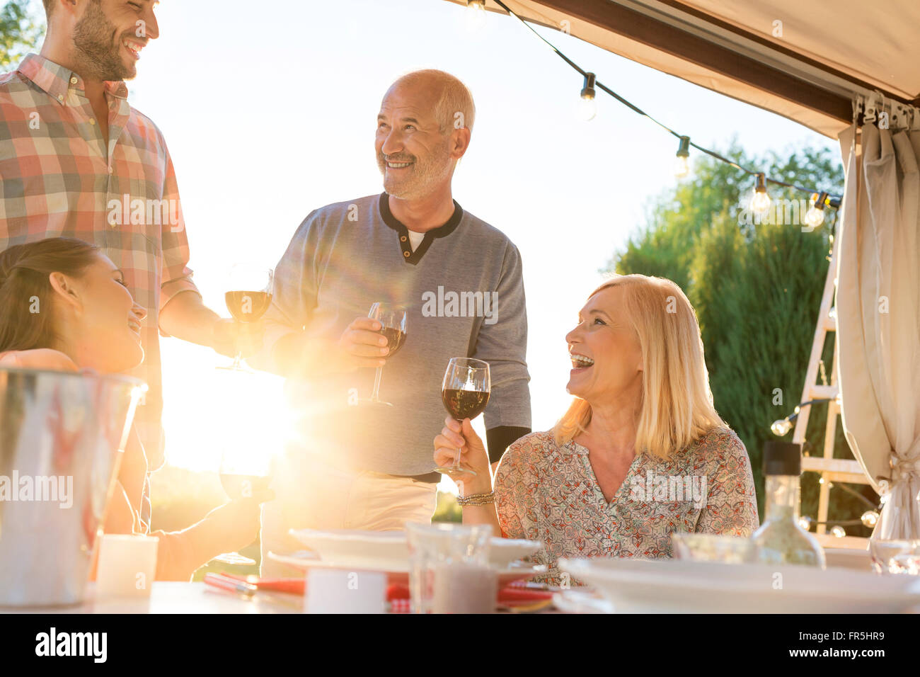 Familia bebiendo vino en el soleado patio tabla Foto de stock