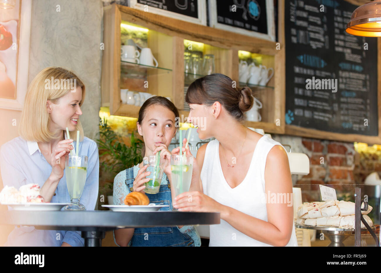 Madre e hija bebiendo limonada en el café la tabla Foto de stock