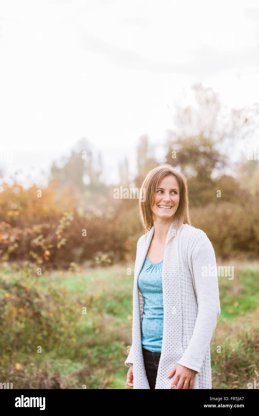 Mujer sonriente mirar lejos en el parque de otoño Foto de stock