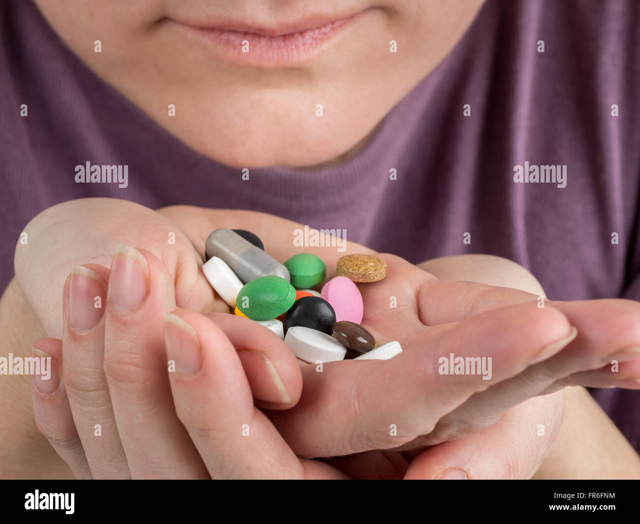 Primer plano de una mujer de raza blanca manos la celebración de todo tipo de píldoras y tabletas cerca de su boca Foto de stock